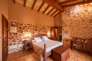 1 dormitorio con cama y pared de piedra en Agroturismo Es Quatre Cantons, en Binisalem