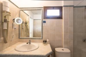 
a bathroom with a toilet, sink, and mirror at Hotel Bahía in La Savina
