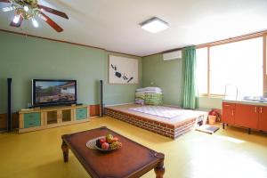 a living room with a television and a table at Dasanbang Pension in Yangyang