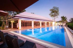 a large swimming pool with chairs and a building at Baan Imm Sook Resort in Chao Lao Beach