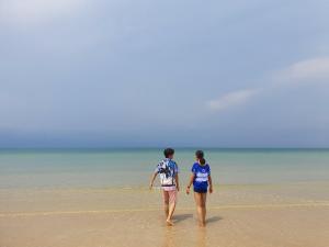 two people walking in the water on the beach at Baan Imm Sook Resort in Chao Lao Beach