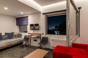 a living room with a couch and a table and a window at AthinA STREETAPARTMENTS in Athens