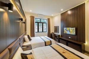 a hotel room with two beds and a tv at Starlight Boutique Hotel in Quang Ninh