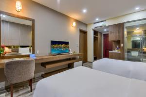 1 dormitorio con 1 cama y escritorio con TV en MANLI Resort Quảng Bình, en Dong Hoi
