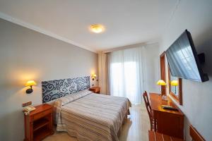 a bedroom with a bed and a desk and a television at Hotel Bajamar Centro in Nerja