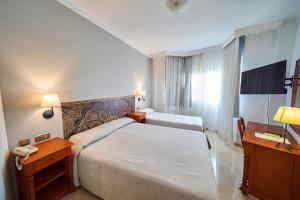a hotel room with a bed and a television at Hotel Bajamar Centro in Nerja