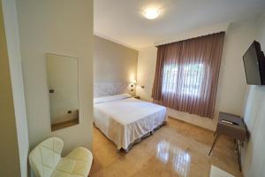 a bedroom with a bed and a mirror and a window at Hotel Bajamar Centro in Nerja