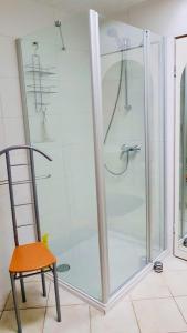 a shower with a glass door next to a chair at Ferienwohnung Boller II in Marktredwitz