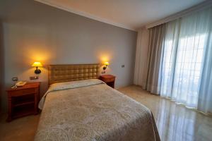 a bedroom with a bed and two tables and a window at Hotel Bajamar Centro in Nerja