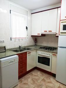 una cocina con armarios blancos y fregadero en Apartamentos Querol, en Valderrobres