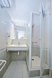 uma casa de banho com um chuveiro, um lavatório e um espelho. em Azur Hotel em Balaruc-les-Bains