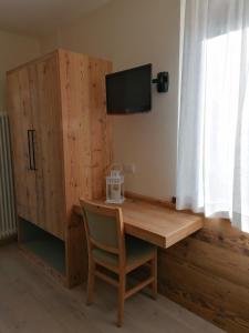 a wooden desk with a tv and a cabinet at Albergo Silvana in Ledro