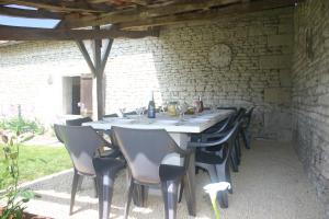 einen langen Tisch mit Stühlen und eine Steinmauer in der Unterkunft L'ancienne cave in Prinçay