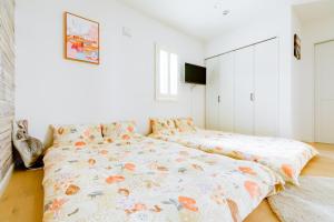 una camera bianca con un letto con un copriletto floreale. di サンライズハワイ ad Osaka