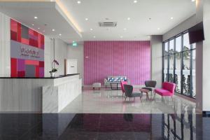 een lobby met stoelen en een roze muur bij favehotel Hasyim Ashari Tangerang in Tangerang