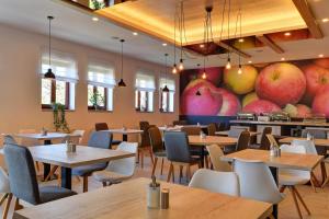 un restaurante con mesas y sillas y un gran mural de manzanas en Hotel Grunt en Mladá Boleslav