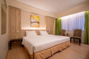 una habitación de hotel con una cama grande y una mesa en The Residence Rajtaevee Hotel, en Bangkok