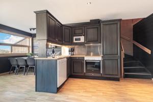 a kitchen with dark wood cabinets and a staircase at Skiers Lodge 2 - Saga Apartments in Hemsedal