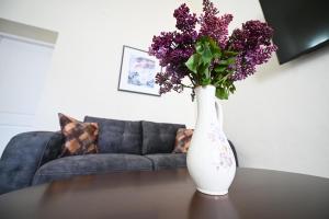a white vase with purple flowers sitting on a table at Casa ABA in Sibiu