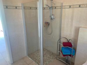 a shower with a glass door and a red stool at Bungalow in Werder am Glindower See in Werder