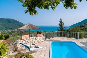 a swimming pool with an umbrella and a chair next to at Vasiliki Cottages in Vasiliki