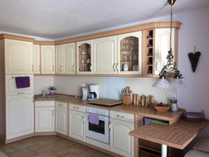 a kitchen with white cabinets and a wooden table at Ferienwohnung "Am Geiseltal" in Merseburg