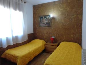 サン・フェリウ・デ・ギホルスにあるVilla ceciliaの黄色のシーツと窓が備わる客室のベッド2台分です。