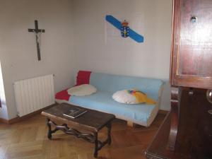una sala de estar con un sofá azul y una cruz en la pared en Gîte La Bastide, en Tournon-dʼAgenais