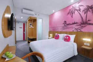 a bedroom with a large white bed with two pink pillows at favehotel Ketapang in Ketapang