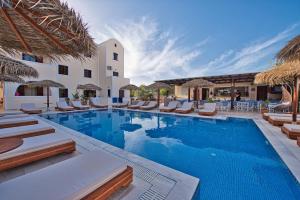 une piscine avec des chaises longues et un complexe hôtelier dans l'établissement Villa Angira, à Kamari