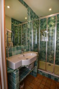baño de azulejos verdes con lavabo y ducha en GITE LES ROCHES, en Moigny