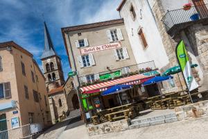 een restaurant met parasols voor een gebouw met een kerk bij Hotel De L'Abbaye in Sauxillanges