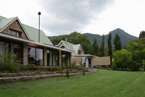 a house with a lawn and mountains in the background at The Clarens Country House in Clarens