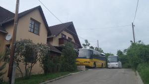 zwei Busse auf einer Straße neben einem Haus in der Unterkunft Legányi Apartmanház in Eger