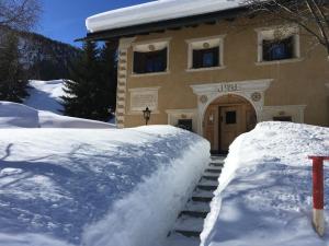 une maison avec un tas de neige devant elle dans l'établissement Chesa Viletta, à La Punt-Chamues-ch