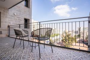 einen Balkon mit 2 Stühlen und Stadtblick in der Unterkunft HolySuite Even Israel in Jerusalem