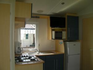 カルナックにあるCamp-Home emplacement 99, 106,107のキッチン(コンロ、シンク付)、窓が備わります。