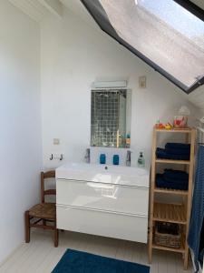 a bathroom with a white sink and a chair at Vakantiehuis Haspengouw - Pastorij Mettekoven in Mettekoven