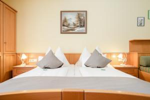 a bedroom with a large white bed with two pillows at Pension Glitschnerhof in Aigen im Ennstal