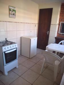 a kitchen with a stove and a refrigerator and a table at Pousada Santa Felicidade Trieste D in Curitiba