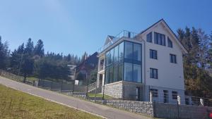 a white house with glass windows on a hill at Apartamenty KADO in Karpacz