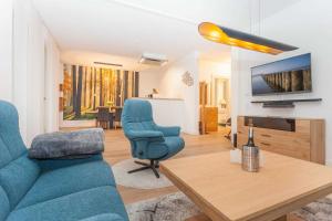 a living room with a blue couch and a tv at FIRST Wellentraum in Ostseebad Sellin