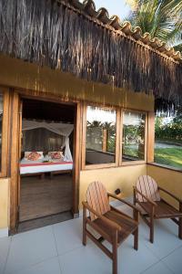 a room with two chairs and a bed and windows at Txai Resort in Itacaré