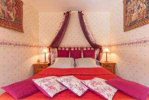 a bedroom with a large red bed with two pillows at La Vigne du Pont in Vieux-Château