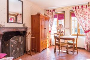 ein Wohnzimmer mit einem Kamin, einem Tisch und Stühlen in der Unterkunft La Vigne du Pont in Vieux-Château