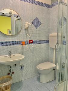 uma casa de banho com um WC, um lavatório e um espelho. em Albergo Cinzia em Florença