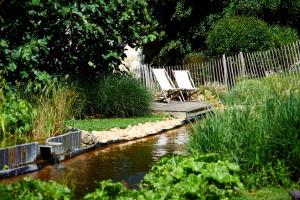 zwei Stühle auf einem Steg neben einem Fluss in der Unterkunft Domaine de la Juranvillerie, gîte et chambres d'hôtes in Rigny-Ussé