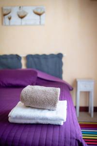 una pila de toallas sentadas encima de una cama púrpura en HotelLe MaraisCaillebotte, en Challans