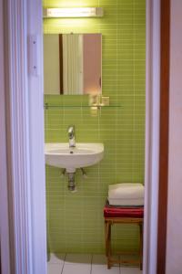 Baño verde con lavabo y espejo en HotelLe MaraisCaillebotte, en Challans
