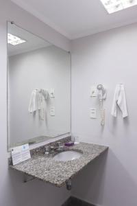 La salle de bains est pourvue d'un lavabo et d'un grand miroir. dans l'établissement Hotel Rojas All Suite, à São Paulo